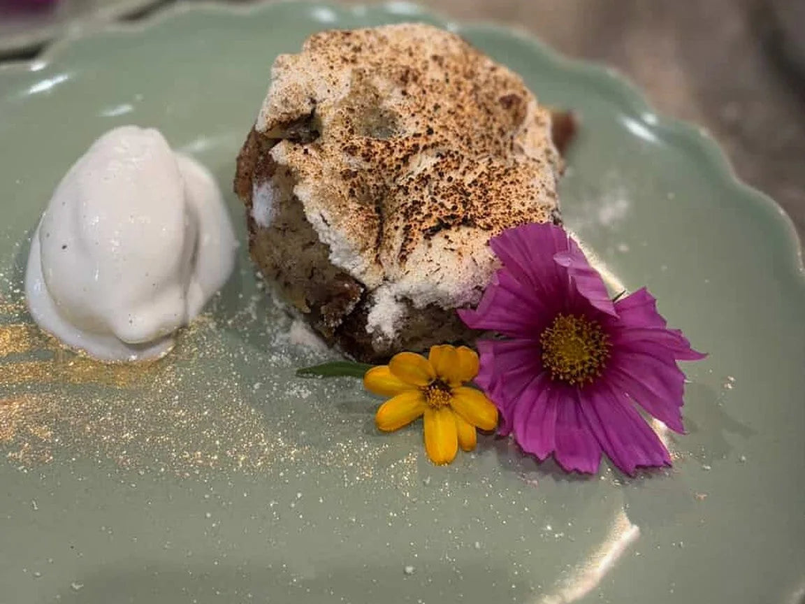 A dessert with whipped cream, crumble and edible flowers