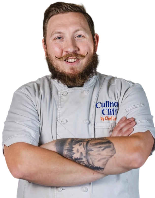 Chef Wade Loucks in his Culinary Cliffs chef's coat, arms folded, smiling